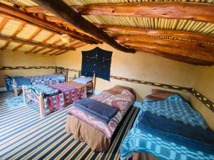 a bedroom with three beds and a roof at Desert Tours & Camp Chraika in Mhamid