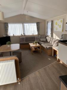 a living room with a couch and a table at Gold Plus 6 Berth Caravan in NEW BEACH with parking WiFi and decking in Dymchurch