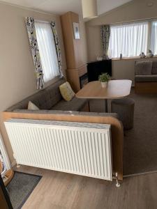 a living room with a couch and a table at Gold Plus 6 Berth Caravan in NEW BEACH with parking WiFi and decking in Dymchurch