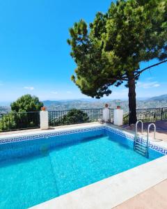 una piscina con un árbol y montañas en el fondo en Lovely 2 Bed Apartment with Stunning views & Pool en Cómpeta