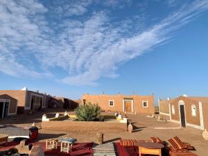 uma vista para um deserto com cadeiras e edifícios em Desert Tours & Camp Chraika em M'hamid