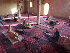 a group of people doing yoga on the floor at Desert Tours & Camp Chraika in Mhamid
