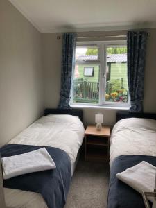 two beds in a small room with a window at Beautiful and Tranquil Lakeside Lodge - Sleeps 5 in Northampton