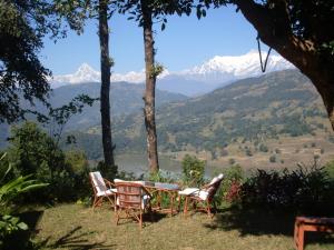 una mesa y sillas con vistas a las montañas en Dinesh House, en Pokhara