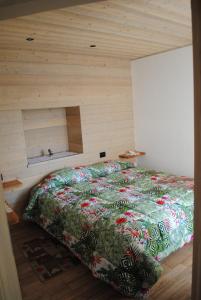 Cama en habitación con pared de madera en Casa Vacanza San Martino, en Fondo