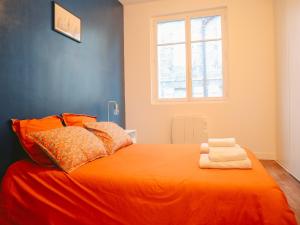 een slaapkamer met een oranje bed en een raam bij Balcon du Champ de Mars - Wifi / Parking in Angoulême