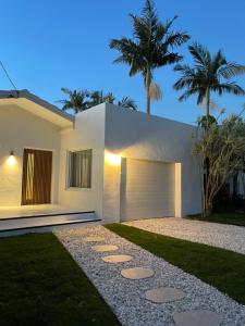a white house with a garage and palm trees at Entre Palmas Ballina in Ballina
