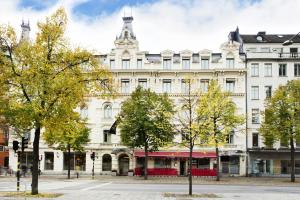 a large white building with trees in front of it at Elite Hotel Stockholm Plaza in Stockholm