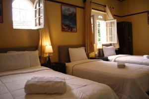 two beds in a room with two windows at Lion Backpackers in Lima