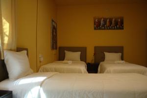2 camas en una habitación de hotel con sábanas blancas en Lion Backpackers, en Lima