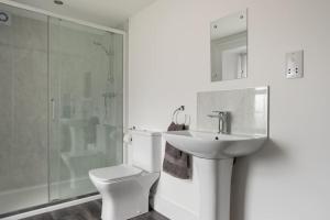 a white bathroom with a toilet and a sink at Beautiful Detached House, just metres from the sea in Gourdon