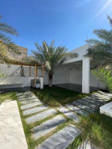 une maison avec des palmiers à côté d'une passerelle dans l'établissement MY HOTEL Al Lathba Pool Villa - Nizwa فيلا اللثبه-نزوى, à Nizwa