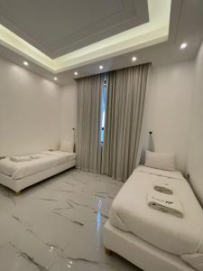 a white room with two beds and a window at MY HOTEL Al Lathba Pool Villa - Nizwa فيلا اللثبه-نزوى in Nizwa