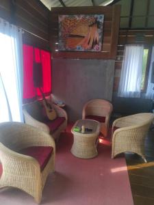 ein Zimmer mit Stühlen, einem Tisch und einer Gitarre in der Unterkunft Air Manis Secret Surfcamp in Taluk Batung