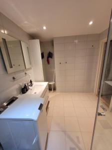 La salle de bains blanche est pourvue d'une douche et d'un lavabo. dans l'établissement Espeland, à Bergen