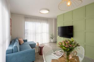 a living room with a blue couch and a tv at YalaRent Flora- Designed 1BR penthouse in Florentin in Tel Aviv