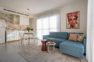 a living room with a blue couch and a kitchen at YalaRent Flora- Designed 1BR penthouse in Florentin in Tel Aviv
