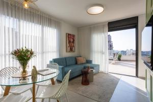 uma sala de estar com um sofá azul e uma mesa de vidro em YalaRent Flora- Designed 1BR penthouse in Florentin em Tel Aviv