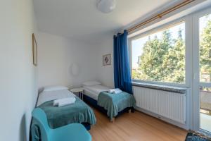 a bedroom with two beds and a large window at Horyzont Apartamenty -Domek na Sosnowej z tarasem in Kołobrzeg