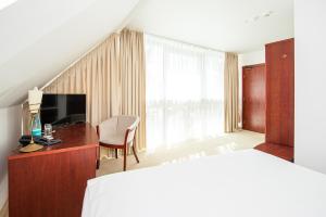 a bedroom with a bed and a desk and a television at Hotel Medūna in Druskininkai