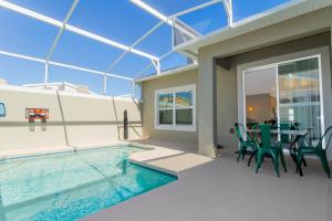 a house with a swimming pool and a table and chairs at Gorgeous 5 Bd w/ Pool Close to Disney @ Champions Gate 948 in Kissimmee