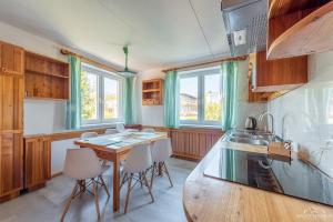 uma cozinha com uma mesa e cadeiras de madeira e janelas em Horyzont Apartamenty -Domek na Sosnowej z tarasem em Colberga