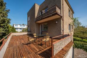 eine Holzterrasse mit einem Tisch und Stühlen auf einem Haus in der Unterkunft Horyzont Apartamenty -Domek na Sosnowej z tarasem in Kołobrzeg