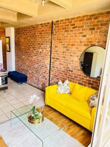 a living room with a yellow couch and a brick wall at Joburg’s Cutest Condo. in Johannesburg