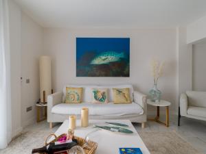 a living room with a white couch and a fish painting at Avatar Las Canteras in Las Palmas de Gran Canaria