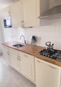 a kitchen with white cabinets and a sink and a stove at KeyCity Apt Near Amsterdam & The Hague in Leiden