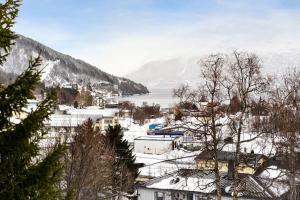 House with garage in central Lyngen في Lyngseidet: مدينة فيها مباني مغطاة بالثلج وبحيرة