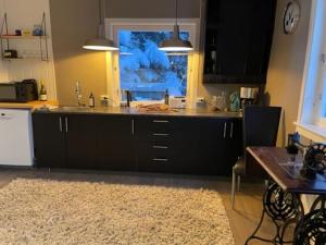 cocina con armarios negros, mesa y ventana en House with garage in central Lyngen, en Lyngseidet