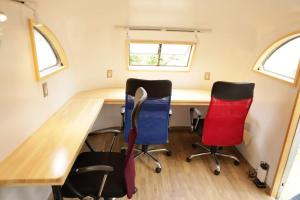 einen Schreibtisch und zwei Stühle in einem winzigen Haus in der Unterkunft Guest House Uminokyojyusya - Vacation STAY 04260v in Miyazaki