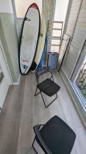 ネタニヤにあるBy the seaの窓の横にサーフボード2枚と椅子が置かれた部屋