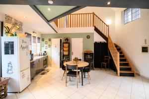 a kitchen and dining room with a table and a staircase at Gîte Cosy Green avec Jardin, espace vintage et jeux de société in Chevincourt