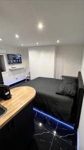 een slaapkamer met een zwart bed met een blauw led-licht bij Bella vita - Studio tout équipé - Tv Netflix - centre ville 100m- Gare 50m - Basilique 200m in Lisieux