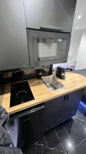 um balcão de cozinha com um lavatório e um micro-ondas em Bella vita - Studio tout équipé - Tv Netflix - centre ville 100m- Gare 50m - Basilique 200m em Lisieux