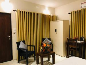 um quarto com duas cadeiras e uma mesa com flores em Ceylon Kingsmen Garden Hotel - Katunayake em Negombo