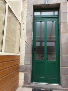 a green door on the side of a building at Les Iris Véranda Parcking in Le Mont-Dore