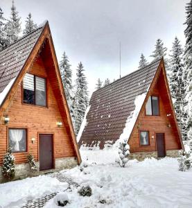 una baita di tronchi nella neve con alberi di Belvedere Villas a Dospat