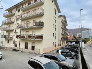 un grande edificio bianco con auto parcheggiate in un parcheggio di L'AQUILA 99 HOME a L'Aquila