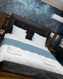 sypialnia z dużym łóżkiem z niebieską ścianą w obiekcie Hotel Premium w Prisztinie