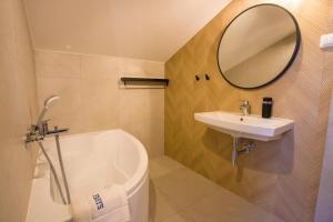 a bathroom with a sink and a tub and a mirror at Farys - świetna lokalizacja, sauna, jacuzzi, piękne widoki z okien in Krynica Zdrój