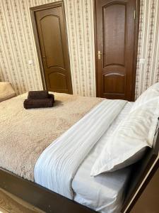 a bed with white sheets and a brown door at Книжный Город in Almaty