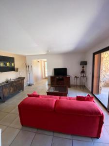 un soggiorno con un divano rosso e una TV di Maison L'Oranger avec piscine - Domaine E Case di Cuttoli a Cuttoli-Corticchiato Altre 3 foto