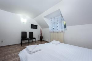 a white bedroom with a bed and two chairs at Pensiunea Ursuletul Paddington in Predeal