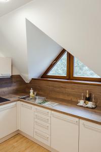 a kitchen with white cabinets and a large window at Villa Silvia in Zuberec