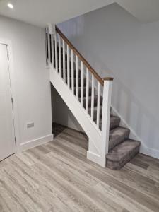 a white staircase in a home with wooden floors at Luxury 3 Bed House, Parking, Garden and 2 Office desks 2 in Southbourne