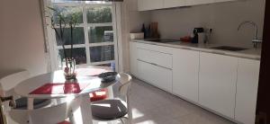 a white kitchen with a table and a window at O MEU LAR in Roxos