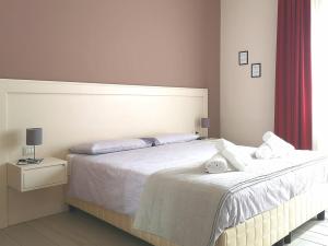 1 dormitorio con 1 cama grande con sábanas y almohadas blancas en Il Balcone di Galatea, en Acireale